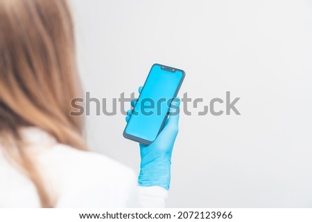 phone in the hands of a doctor. person use a smartphone in medical gloves.