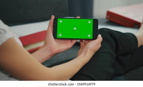 Phone Horizontal Green Screen For Copy Space. Close Up. Chroma Key Mockup. Girl Watching Video Movie On Couch. Home Concept. Back View Woman Hand Phone Holding.