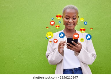 Phone icon, black woman and social media emojis of heart, thumbs up and smile for mockup advertising space. Cellphone, like opinion notification and user typing communication on green background wall - Powered by Shutterstock