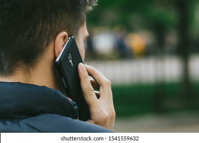 Phone Man Talking On Smartphone. Back View. Technology Mobile Cellphone. Blurred Background.