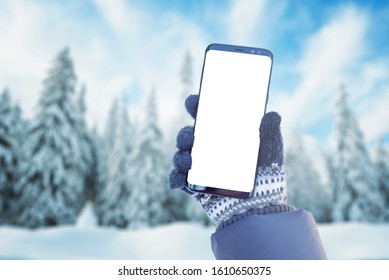 Phone Mockup In Hand With Gloves. Winter, Cold Time With A Lot Of Snow In Mountain. Isolated Screen For Mockup, App Promotion. Snowy Trees In Background