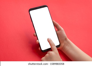 Phone Mockup In Kid Hands. Vertical Position. Isolated Screen For Game, App Propmotion. Red Desk In Background