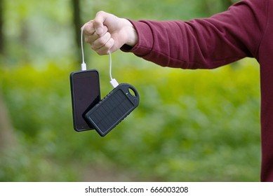 The Phone And The Paver Bank Are Connected By A Cord. A Guy Holds A Paverbank In His Hands With A Phone Holding A String