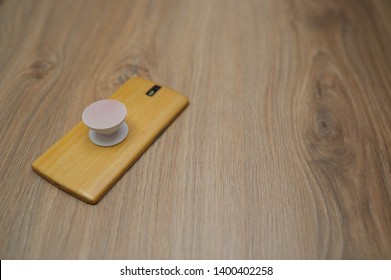 Phone With Pop Socket On Wooden Backgorund.