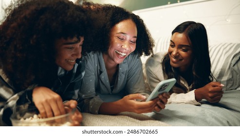 Phone, popcorn and sleepover with friends in bedroom of home together for bonding at night. Funny, laughing and social media with happy people on bed in apartment for evening chilling on weekend - Powered by Shutterstock