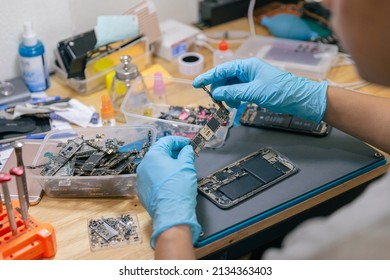 Phone Repair Concept A Repairman Picking The Electronic Part To Assemble With The Mobile Phone With The Tools On The Desk.