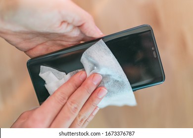 Phone screen disinfecting wipe woman cleaning removing germs with antibacterial wet wipes for corona virus COVID-19 coronavirus prevention. - Powered by Shutterstock