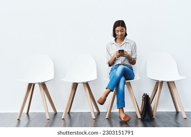 Phone, social media and woman in interview waiting room and search the internet, web or website sitting on chairs. Internship, mockup and young female person texting online ready for a new job - Powered by Shutterstock