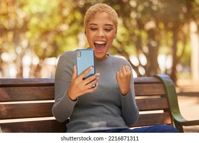 Phone, Success And Woman Excited About Trading On The Internet While On A Bench In The Park. Young, Happy And Girl With Wow Face For Communication On A Mobile App, Celebration And Winning In Nature