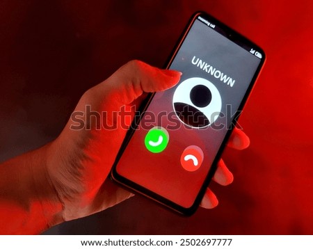 A phone that is receiving a call from an unknown contact who is a scammer. All this is on a black background with a red glow