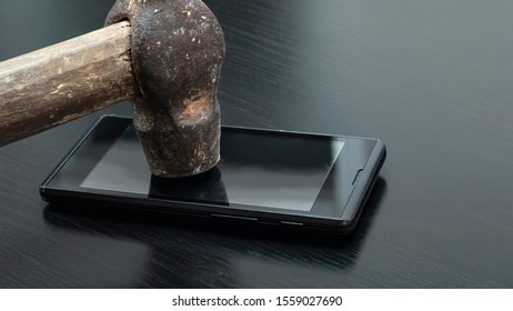 Phone Under Hammer Isolated On Wooden Table