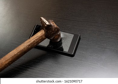 Phone Under Hammer Isolated On Wooden Table