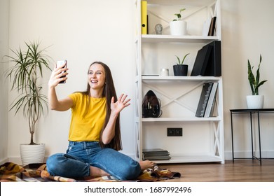 Phone Video Call. A Young Woman Communicates Via Video, Zoom. She Is Sitting On The Floor In A Scandinavian Style Room.