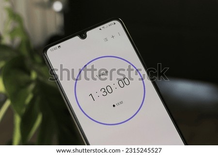 A phone with a white 1 hour and 30 minutes timer on a blurry background