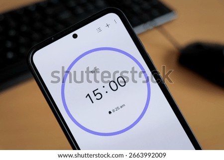Phone white 15-minute timer to study with pomodoro method on laptop keyboard, study business background