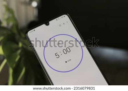 A phone with a white 5-minute timer on a blurry background