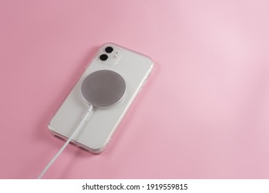 phone with wireless charger on pink background