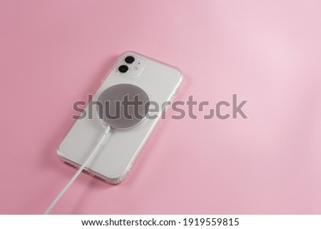 phone with wireless charger on pink background