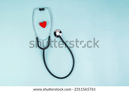 Phonendoscope and red heart on a blue background. The concept of a healthy heart, good health. Red heart and stethoscope. Cardiology, heart health and care, Health Day concept. Copy space.