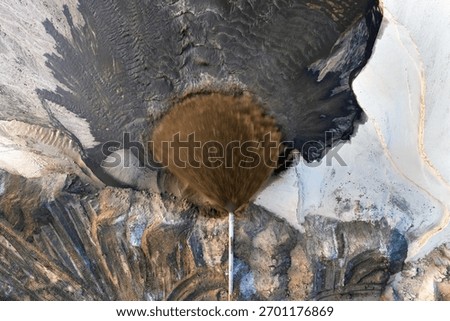 Phosphate mining site in Florida with large pipe ejecting water and sand slurry during mineral extraction process.