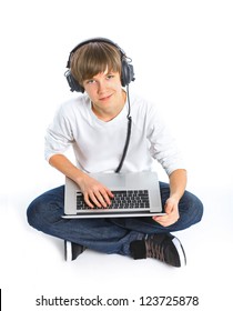 Photo Of An 15 Year Old Boy Wearing Headphones Sitting With A Laptop Computer, Isolated On A White Background.