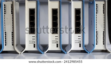 Photo of 5 routers on a table in the corner of a school computer laboratory.                