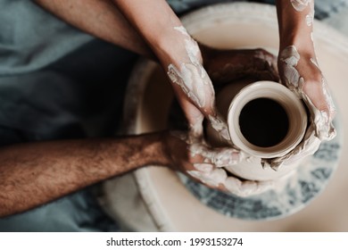 Photo from above. The hands of a man and a woman make a clay vase on a machine using an apparatus. Dating concept - Powered by Shutterstock