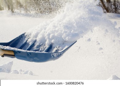 Photo in action. Throwing snow with shovel while cleaning backyard after a heavy snow - Powered by Shutterstock