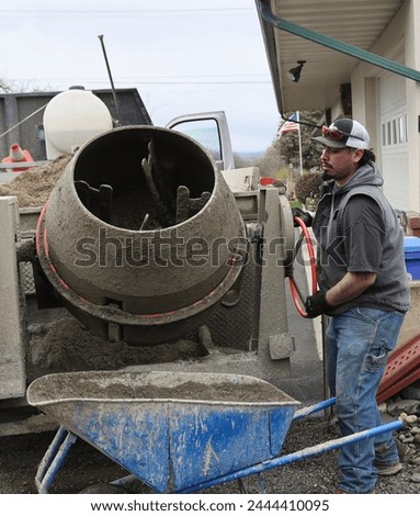 photo of actual laborer mixing and shoveling cement from a cement truck in the process of installing a vinyl fence
