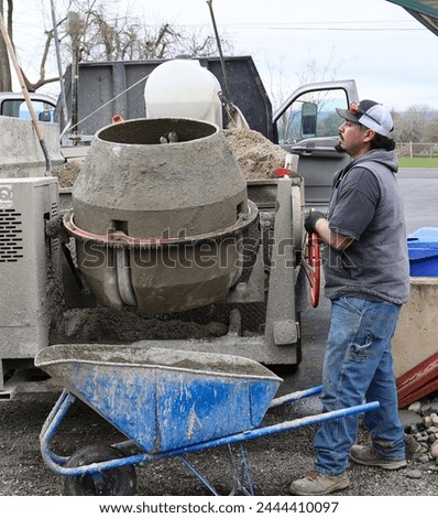 photo of actual laborer mixing and shoveling cement from a cement truck in the process of installing a vinyl fence