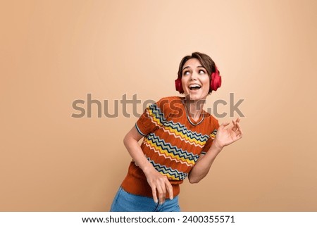 Photo of adorable cheerful girl have good mood listen music headphones dance empty space isolated on beige color background