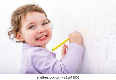 Foto von bezauberndem Kind, das an der Wand zeichnet