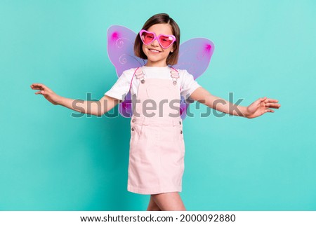 Photo of adorable cute school girl wear pink overall glasses wings smiling dancing isolated teal color background