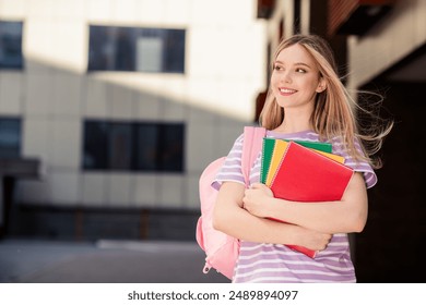 Photo of adorable dreamy lady wear striped t-shirt school bag holding copybooks enjoying walking outdoors urban city street - Powered by Shutterstock