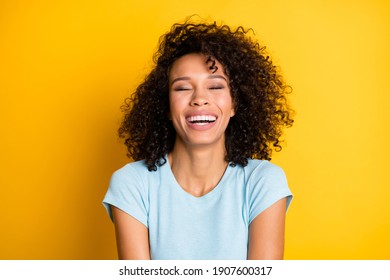 Photo of adorable funny dark skin curly woman dressed blue t-shirt laughing closed eyes isolated yellow color background