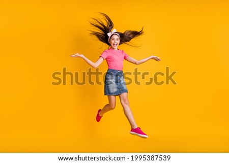 Photo of adorable funny school girl wear pink t-shirt smiling jumping high isolated yellow color background