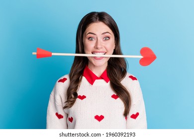 Photo of adorable funny young lady wear hearts print sweater holding teeth cupid arrow isolated blue color background
