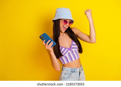 Photo of adorable girl celebrate giveaway victory win clothes from online shop isolated on yellow color background