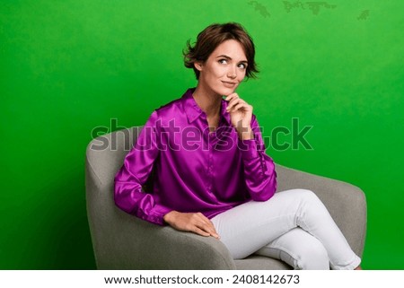 Photo of adorable gorgeous lady sit comfortable chair touch chin look up empty space isolated on green color background