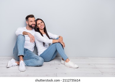 Photo of adorable guy lady dressed white shirts sitting floor looking empty space isolated concrete grey wall background
