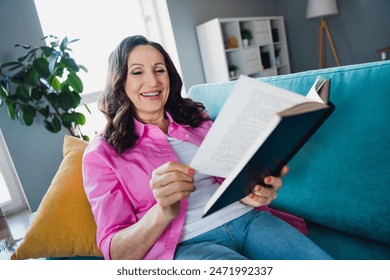 Photo of adorable lovely senior woman sitting sofa reading book enjoying weekend time indoors - Powered by Shutterstock