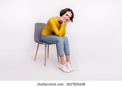 Photo of adorable positive cheerful nice girl hands cheeks sit chair wear yellow shirt isolated grey color background