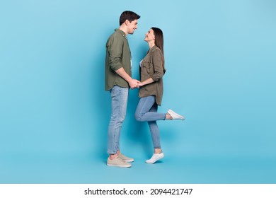 Photo of adorable pretty young lady guy wear green shirts holding arms looking each other ready kissing isolated blue color background - Powered by Shutterstock