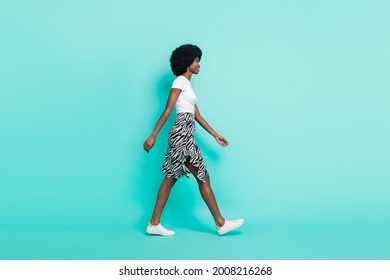 Photo of adorable shiny dark skin lady wear casual clothes smiling walking looking empty space isolated teal color background - Powered by Shutterstock