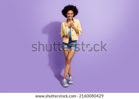Photo of adorable shiny lady wear yellow denim jacket walking smiling isolated violet color background