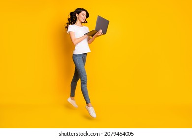 Photo of adorable sweet young woman wear white t-shirt jumping holding modern device empty space isolated yellow color background - Shutterstock ID 2079464005