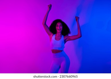 Photo advert sportswear adidas nike reebok brands promo clothes funny young woman fists up crossfit exercises isolated on neon background