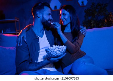 Photo of affectionate carefree lady feed guy pop corn tv watching free time sit couch in late dark room