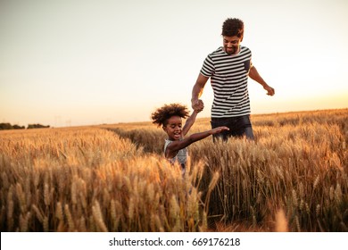 Photo Of An African American Father And Daughter Holding Hands And Having Fun In The Fields.