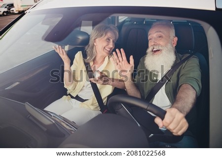 Photo of aged couple husband wife drive automobile transport stop traffic lights dialog laughter outdoors